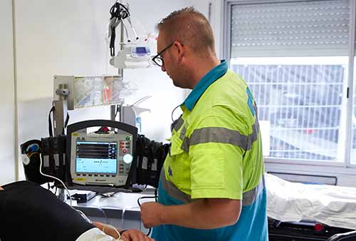 Een ambulancemedewerker van Witte Kruis evenementenzorg in de EHBO post inspecteert de monitor